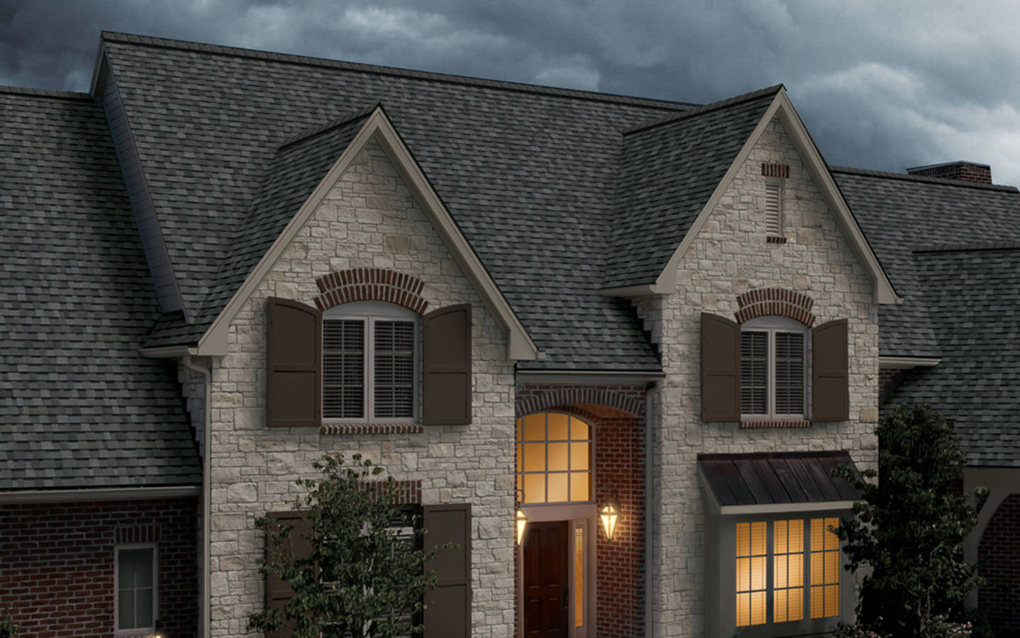 A beautiful home with stone siding and a dark gray shingle roof.